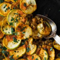 Close-up, overhead shot of vegetarian paella layered with summer squash.