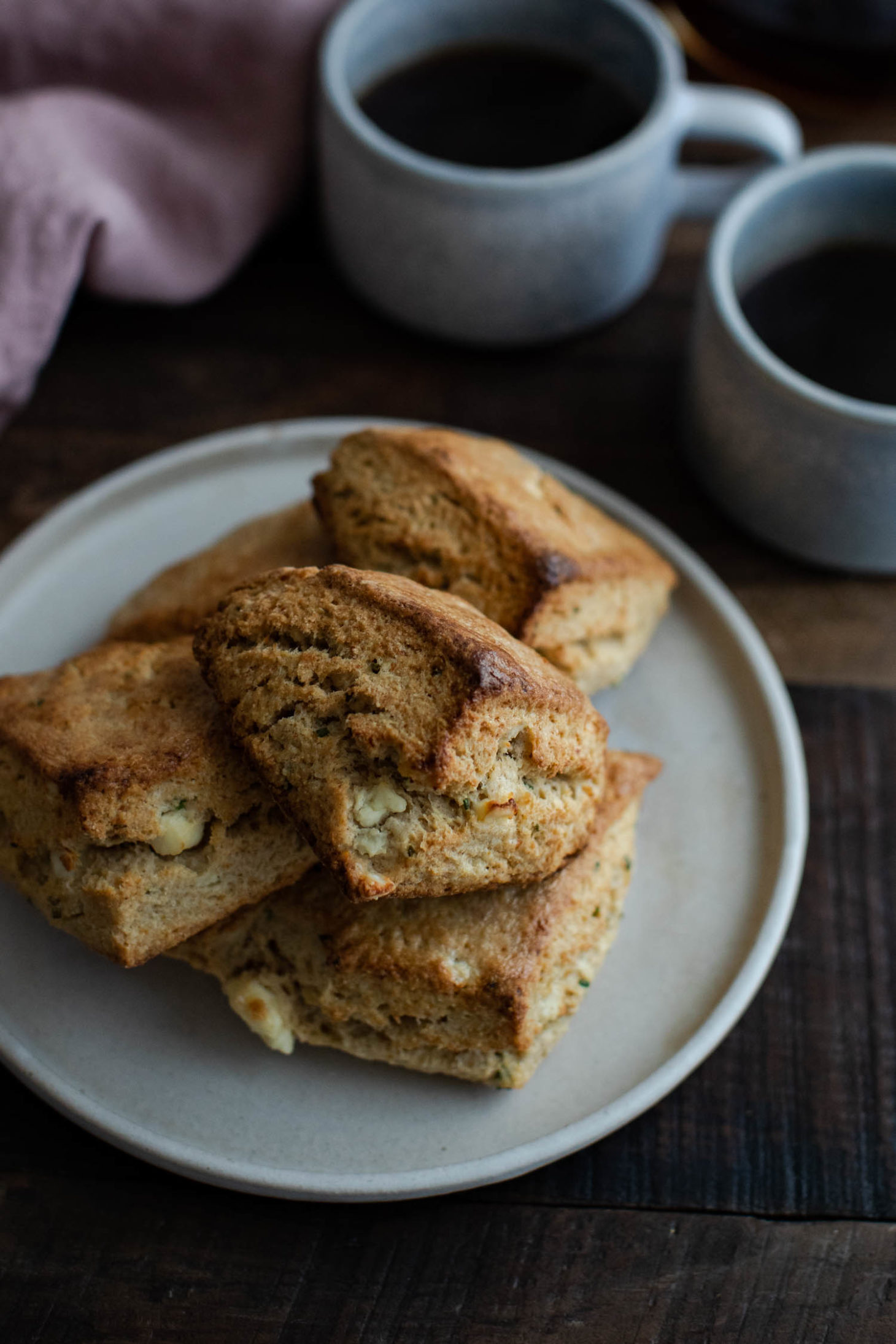 Side angle photo of golden, savory scones filled with feta and chives.