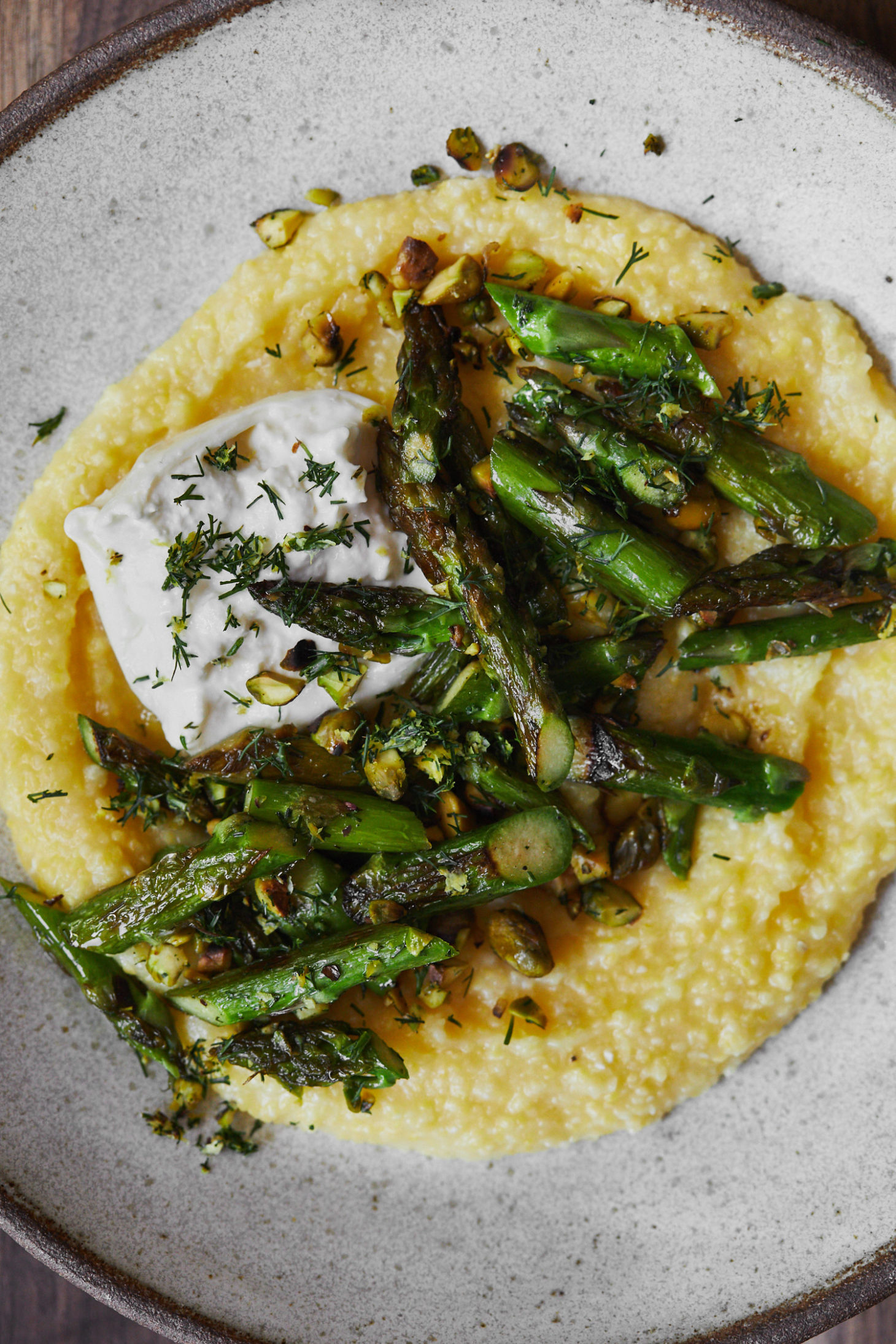 Close-up of asparagus polenta with burrata and a pistachio-dill mix.