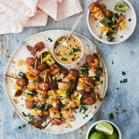 Overhead photograph of halloumi and summer vegetable skewers topped with a chipotle peanut sauce