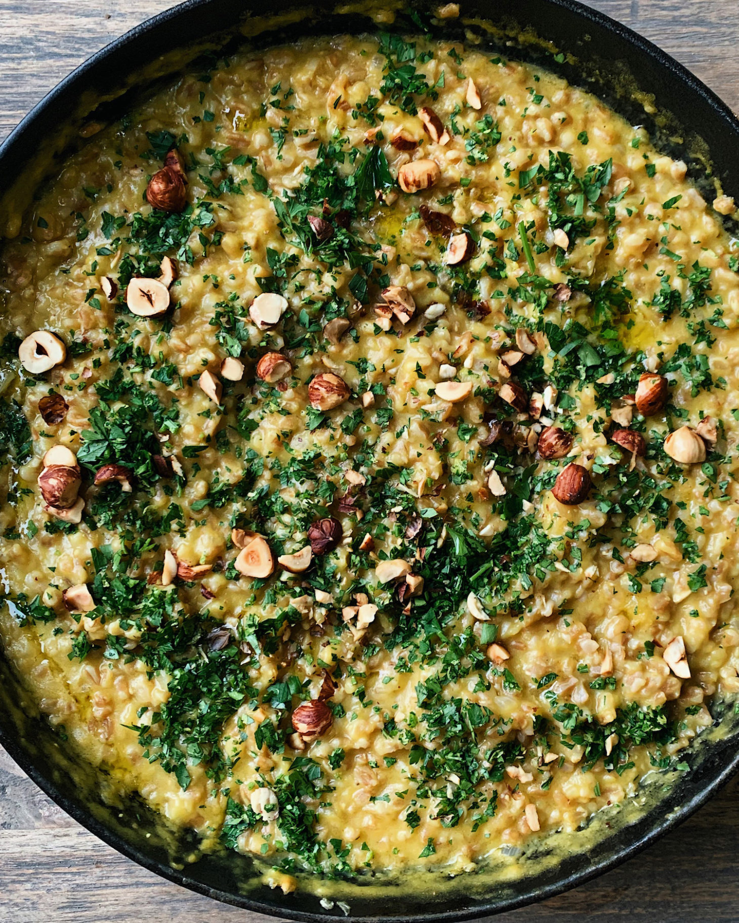 Close-up photograph of farro risotto with acorn squash puree and topped with toasted hazelnuts and gremolata