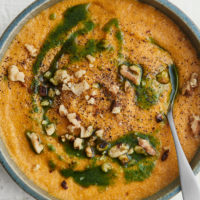 Close-up image of amaranth polenta with carrot puree and topped with parsley oil and walnuts.