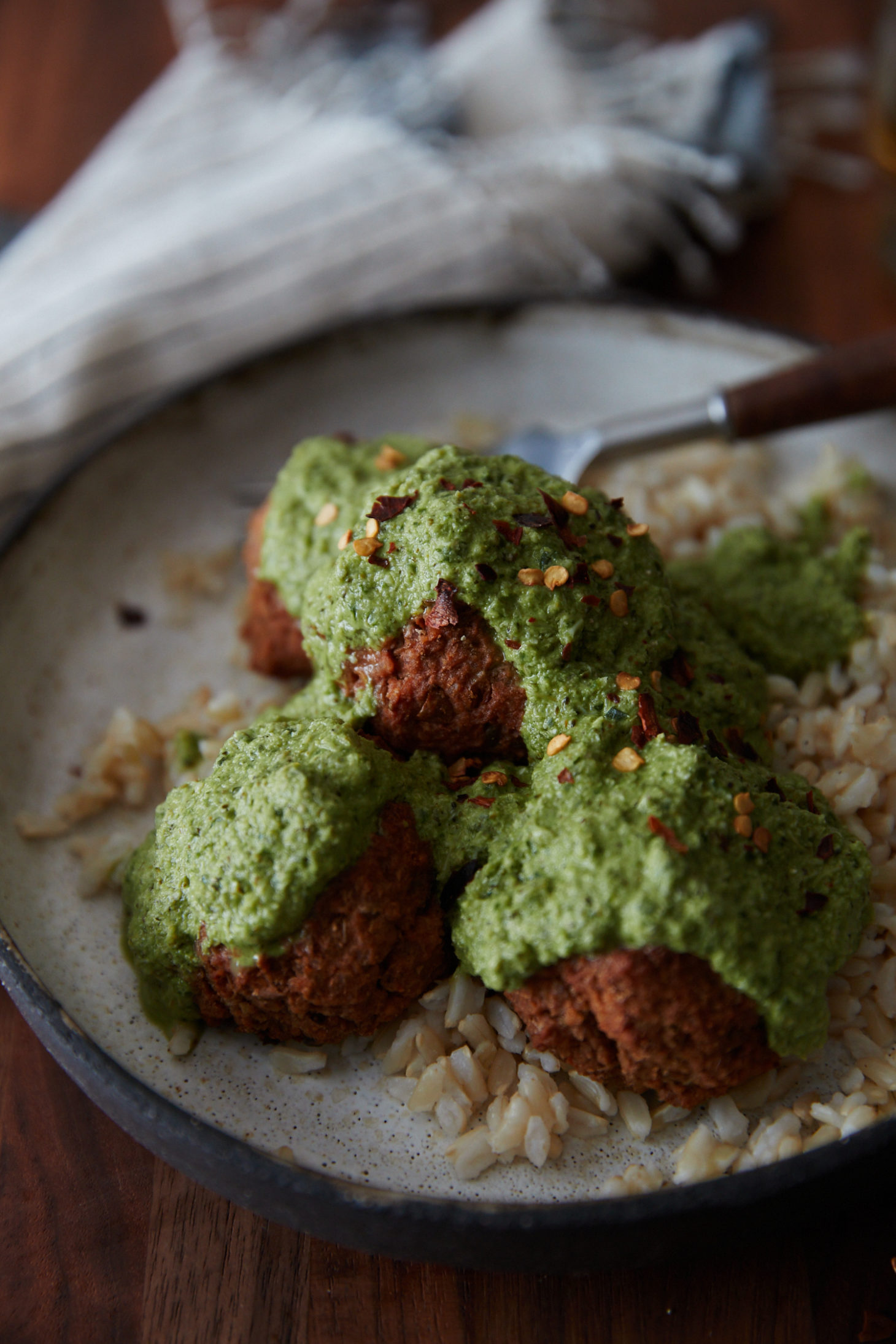 Side-angle photo of a cream bowl with homemade lentil bites with rice and a green broccoli pesto.