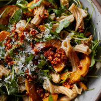 Close-up image of pasta with arugula and delicata squash.