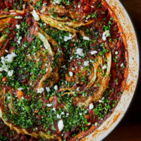 Close-up of cabbage wedges cooked in tomato sauce with white beans.