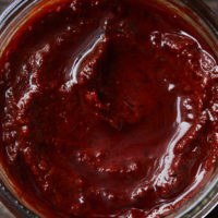 Close-up of a reddish paste in a clear jar.