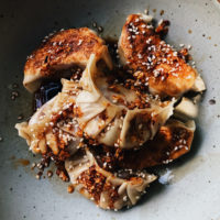 Close-up photo of pleated potstickers in a grey bowl.